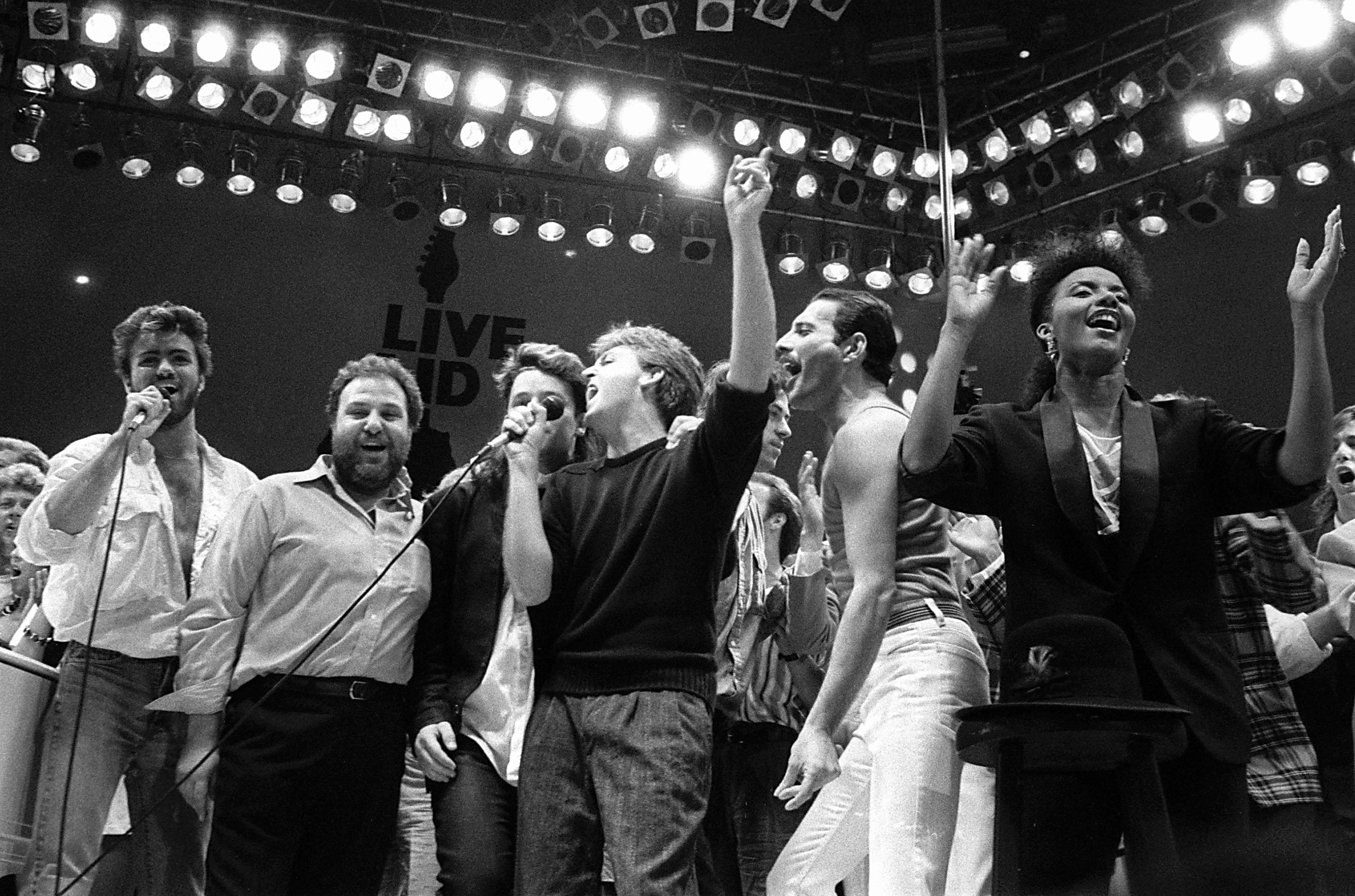From left, George Michael of Wham!, concert promoter Harvey Goldsmith, Bono of U2, Paul McCartney, concert organiser Bob Geldof and Freddie Mercury of Queen join in the finale of the Live Aid famine relief concert, at Wembley Stadium, London, July 13, 1985. (AP Photo/Joe Schaber)